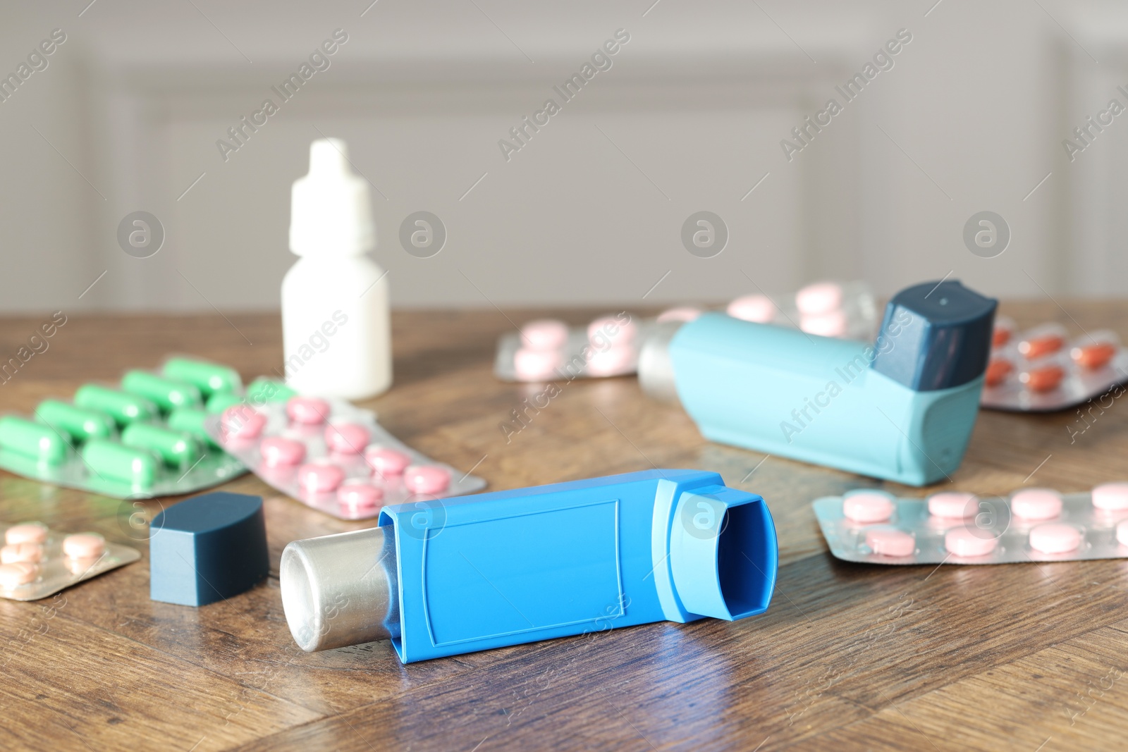 Photo of Different asthma medications on wooden table indoors, closeup