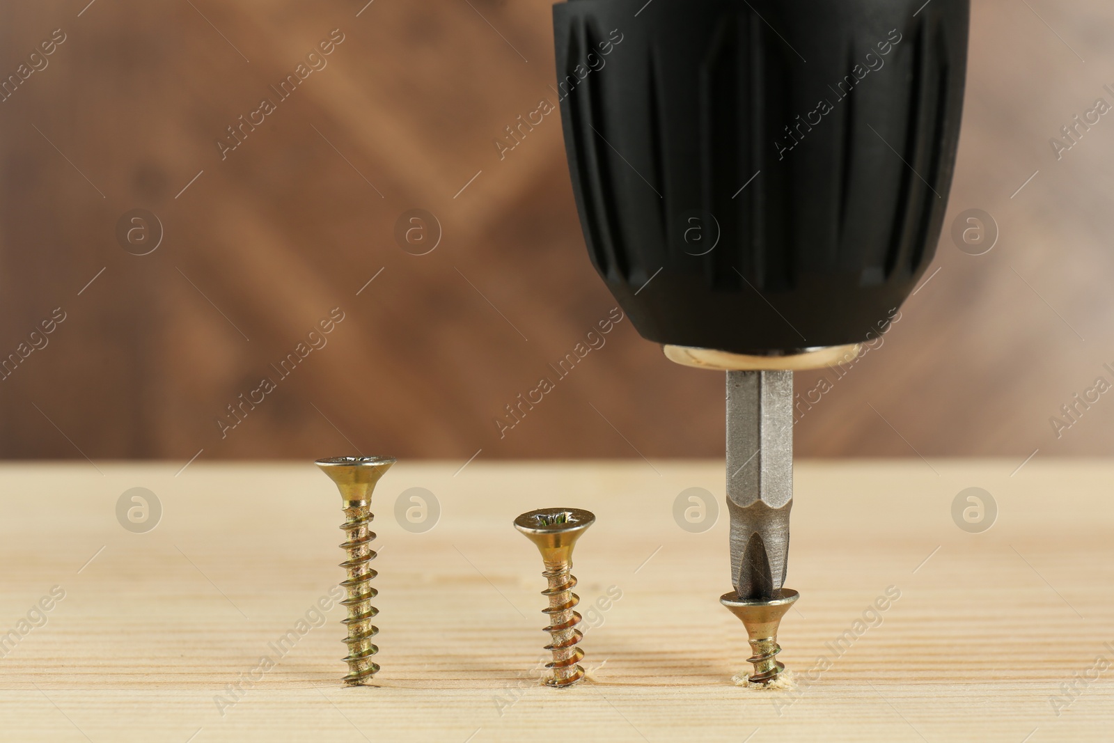 Photo of Screwing screw into wooden plank, closeup view