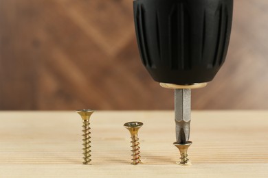 Photo of Screwing screw into wooden plank, closeup view