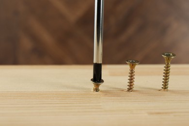 Screwing screw into wooden plank, closeup. Space for text