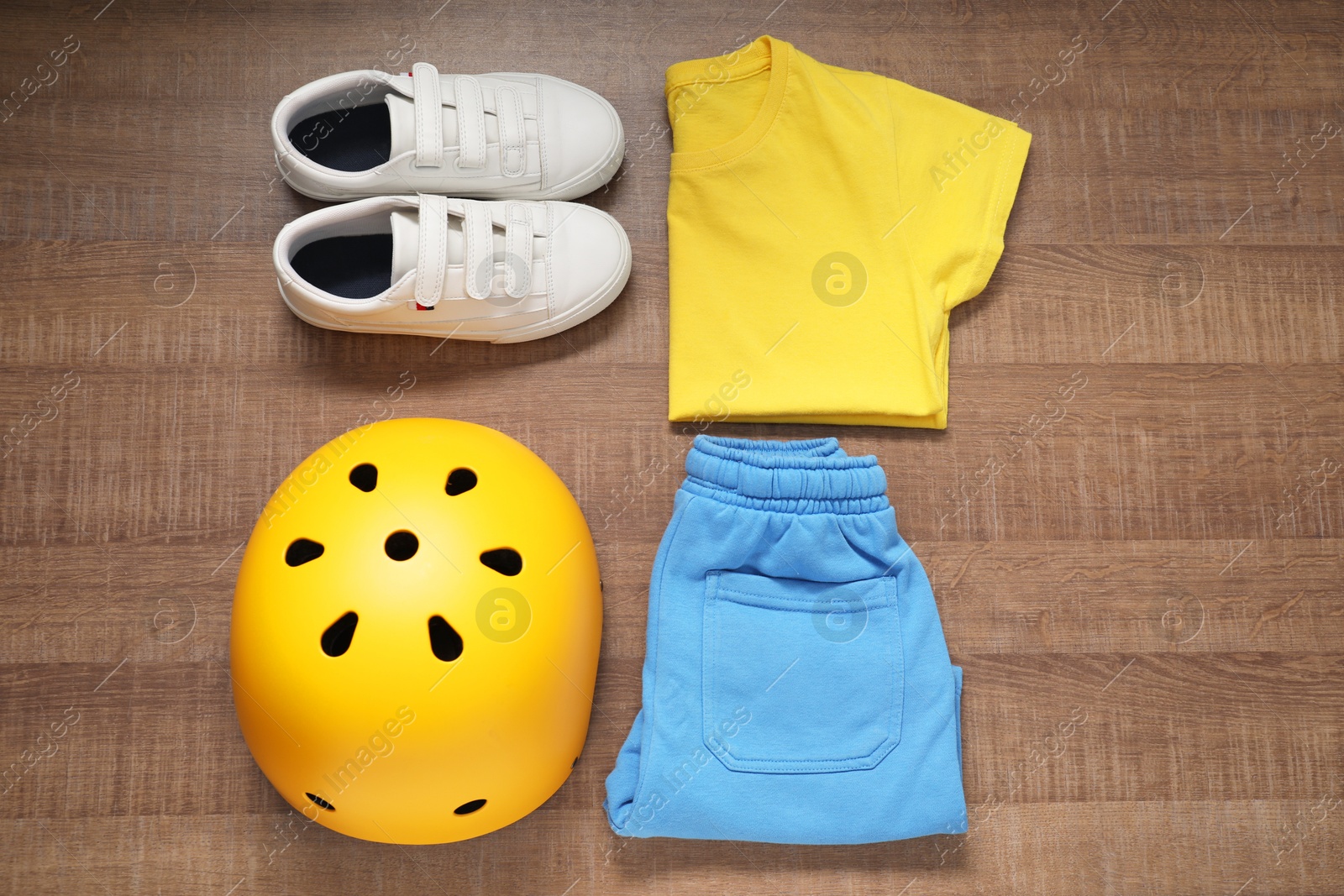 Photo of Bicycle helmet, sneakers and sportswear on wooden background, flat lay