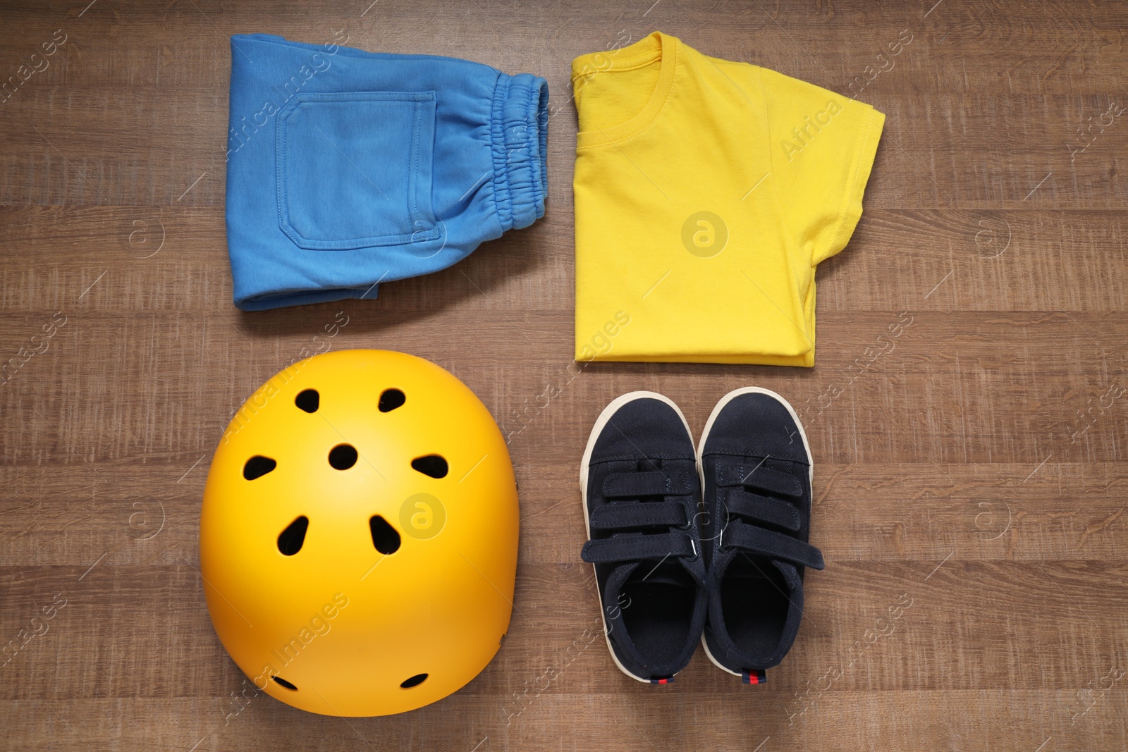 Photo of Bicycle helmet, sneakers and sportswear on wooden background, flat lay