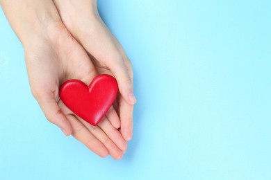 Photo of Woman holding red heart on light blue background, top view. Space for text