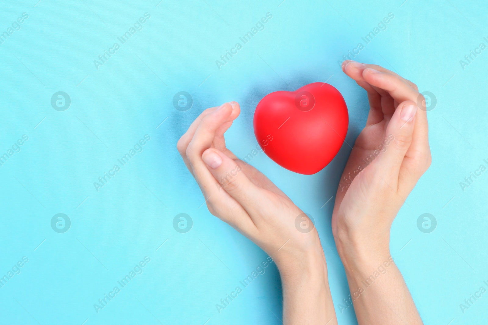 Photo of Woman holding red heart on light blue background, top view. Space for text