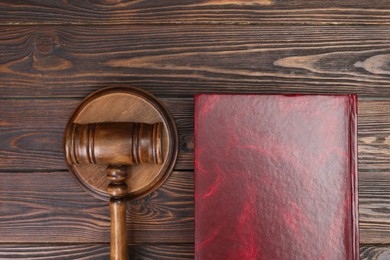 Book and judge's gavel on wooden table, flat lay