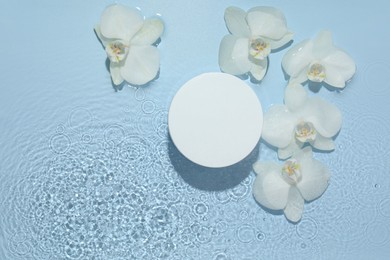 Photo of Product presentation. Beautiful orchid flowers and podium in water on light blue background, flat lay. Space for text