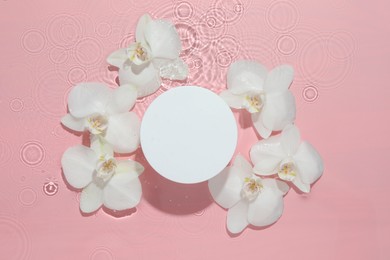 Photo of Beautiful orchid flowers and podium in water on pink background, flat lay. Presentation for product