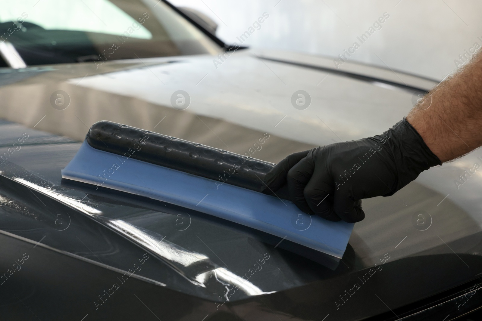 Photo of Man wiping auto with squeegee brush at car wash, closeup