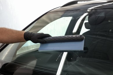 Man wiping auto with squeegee brush at car wash, closeup