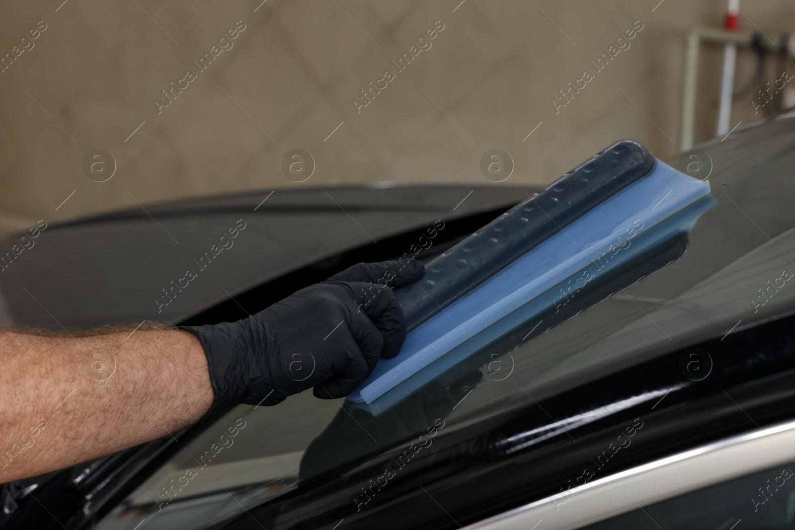 Photo of Man wiping auto with squeegee brush at car wash, closeup