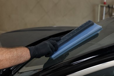 Man wiping auto with squeegee brush at car wash, closeup