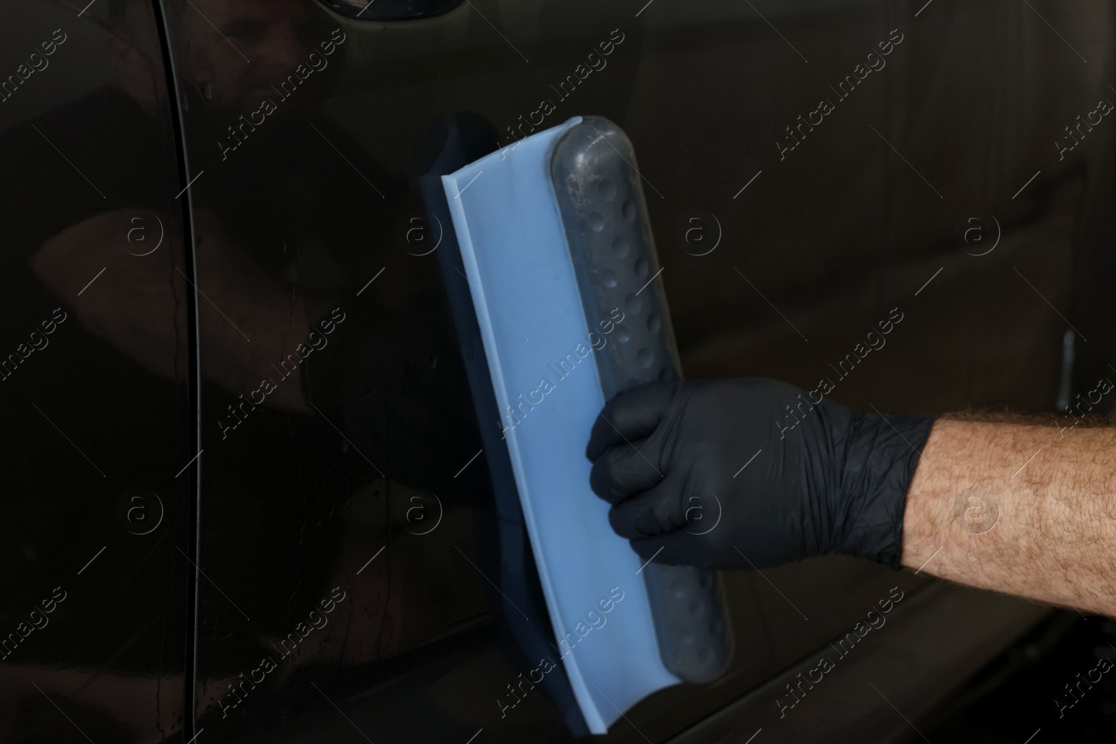 Photo of Man wiping auto with squeegee brush at car wash, closeup