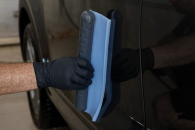 Photo of Man wiping auto with squeegee brush at car wash, closeup