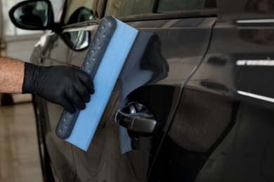 Man wiping auto with squeegee brush at car wash, closeup