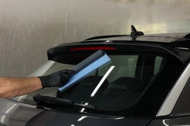 Man wiping auto with squeegee brush at car wash, closeup