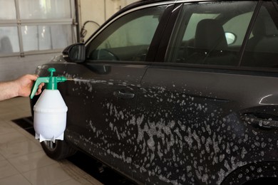 Man washing auto with sprayer at car wash, closeup