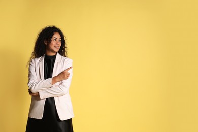 Photo of Beautiful woman in stylish jacket on yellow background, space for text