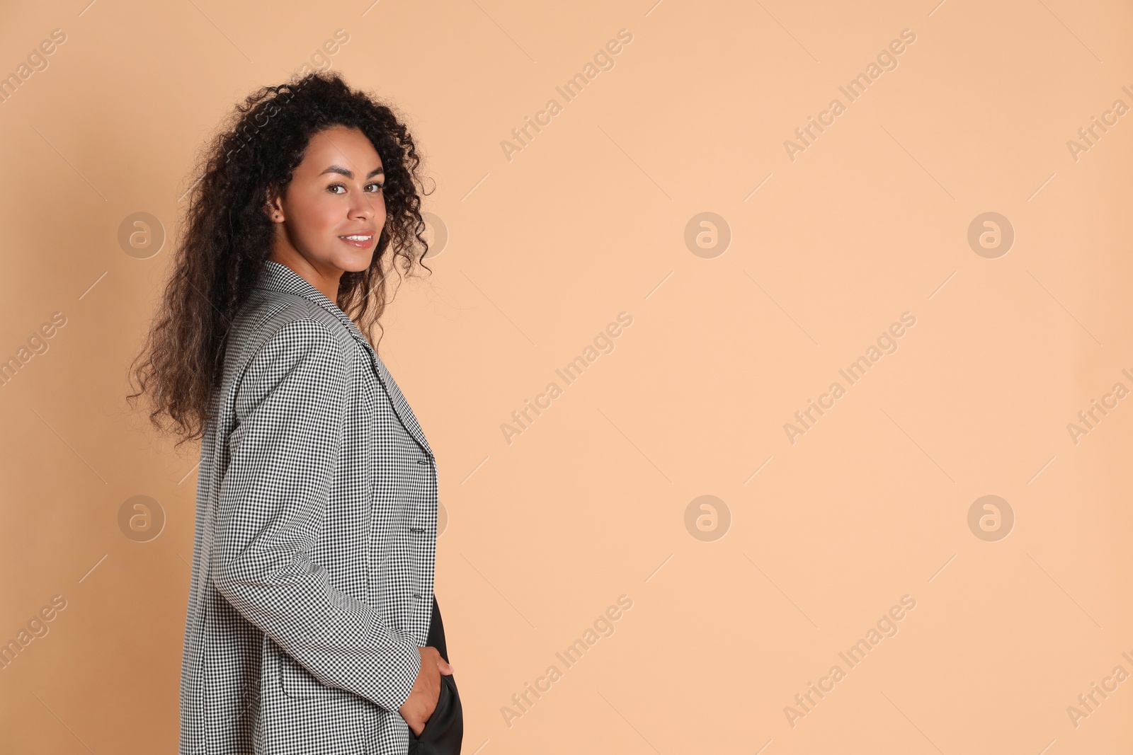 Photo of Beautiful woman in stylish jacket on beige background, space for text