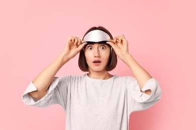 Overslept young woman with sleep mask on pink background