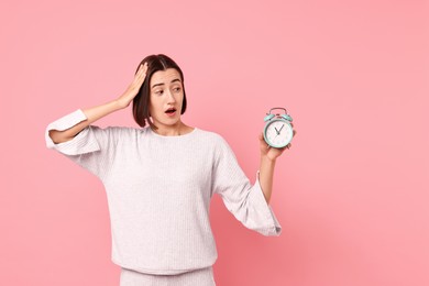 Overslept young woman with alarm clock on pink background. Space for text