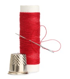 Photo of Thimble and needle with red sewing thread isolated on white