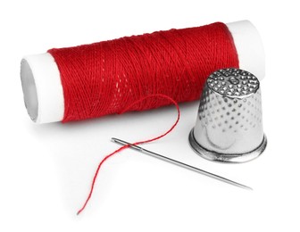 Photo of Thimble and needle with red sewing thread isolated on white