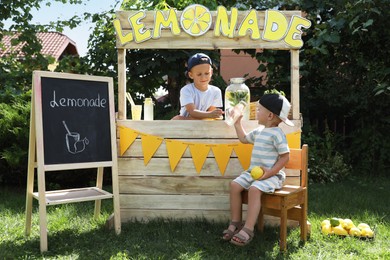 Photo of Cute boys near lemonade stand in park