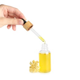 Photo of Woman dripping tincture from pipette into bottle on white background, closeup