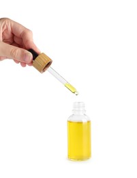 Photo of Woman dripping tincture from pipette into bottle on white background, closeup