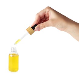 Photo of Woman dripping tincture from pipette into bottle on white background, closeup