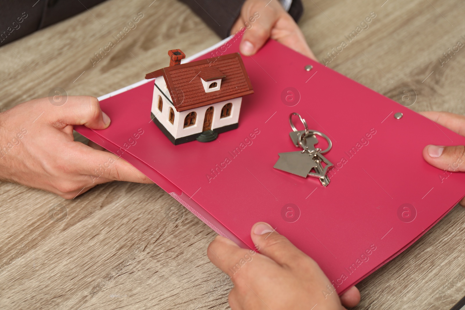 Photo of Real estate agent working with client at wooden table, closeup