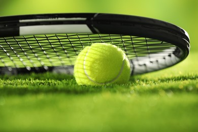 Photo of Tennis racket and ball on green grass, closeup