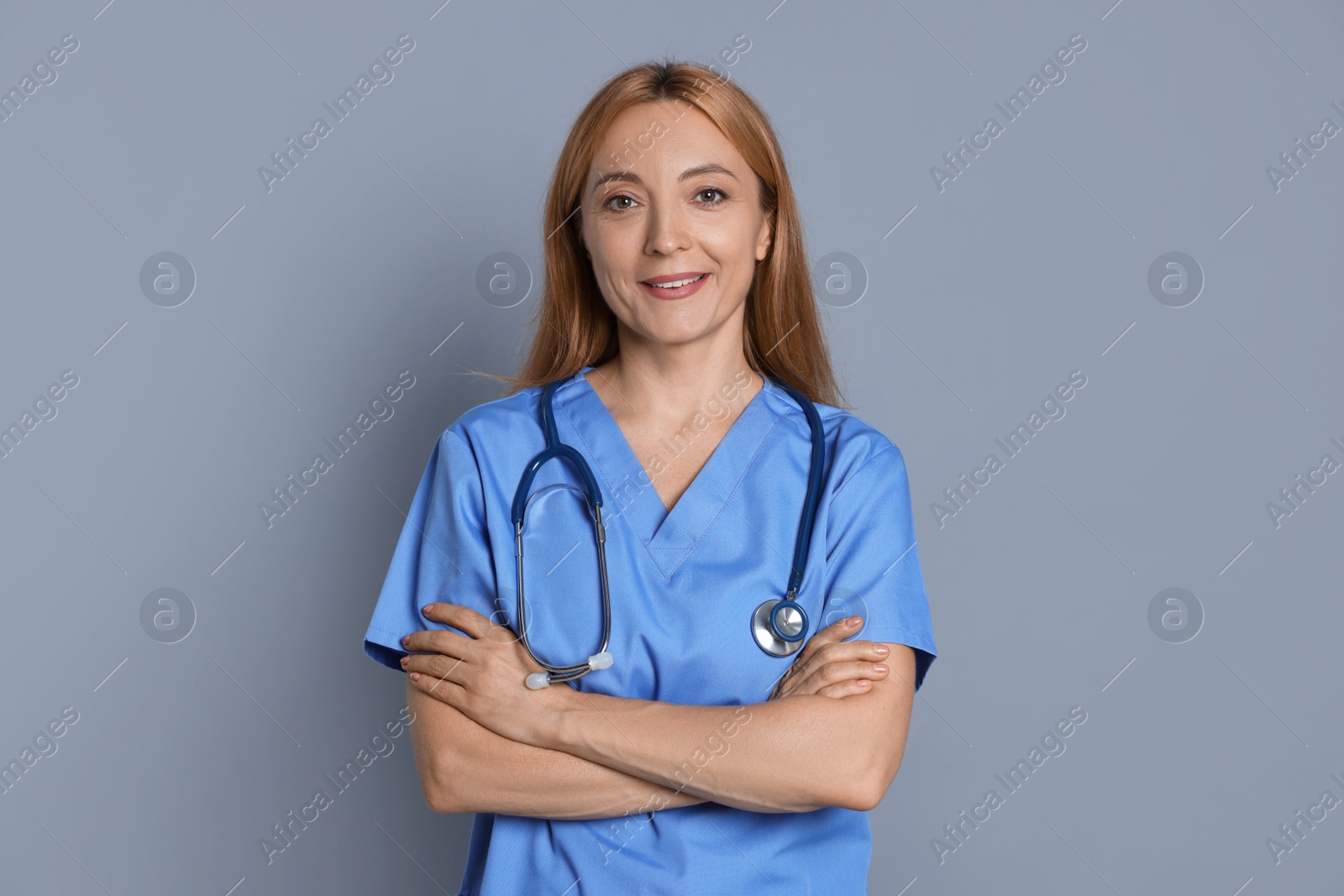 Photo of Smiling doctor with stethoscope on gray background