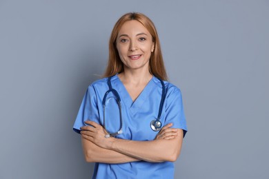 Photo of Smiling doctor with stethoscope on gray background