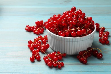 Photo of Fresh red currants in bowl on light blue wooden table