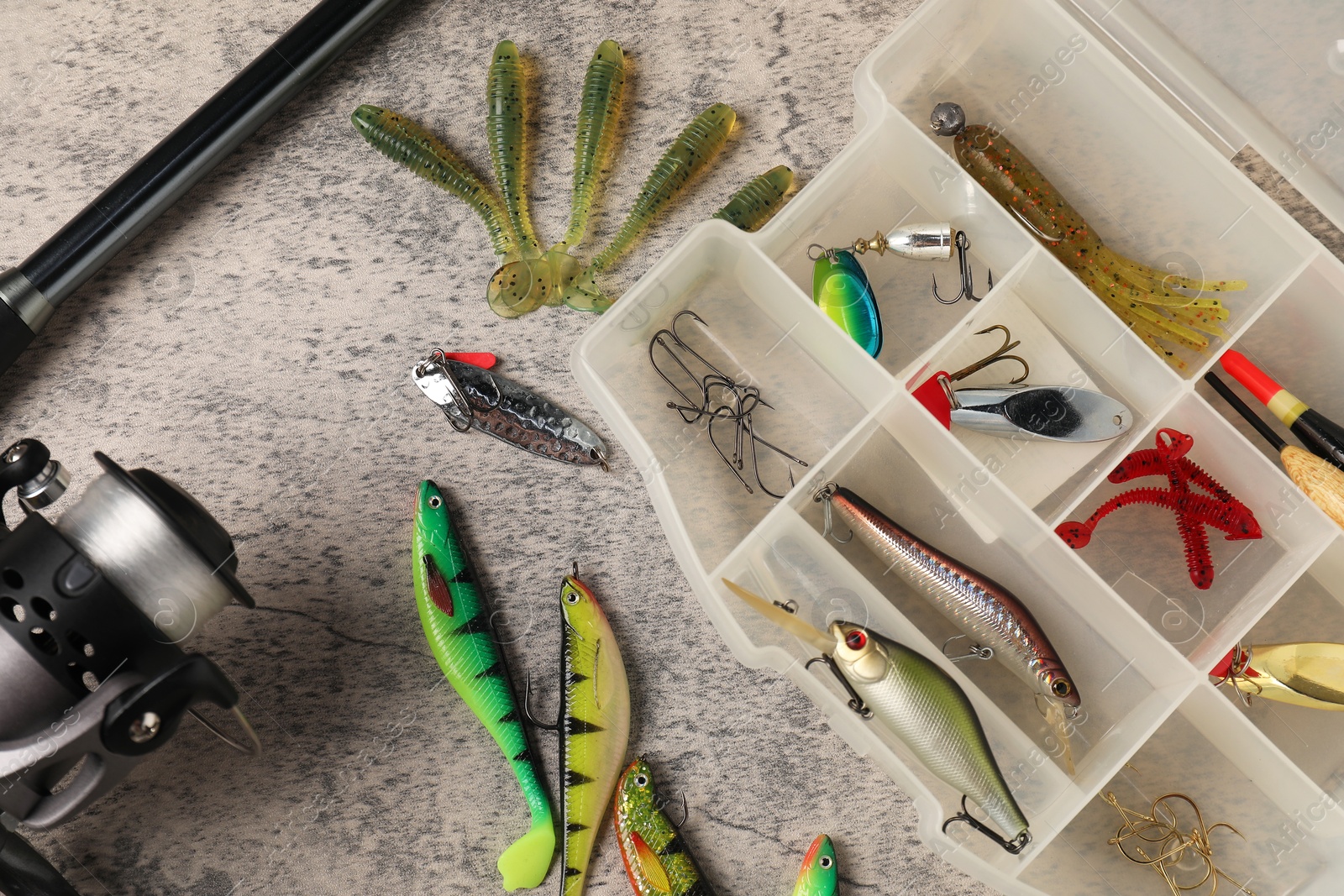 Photo of Fishing baits, hooks and rod with spinning reel on grey table, top view