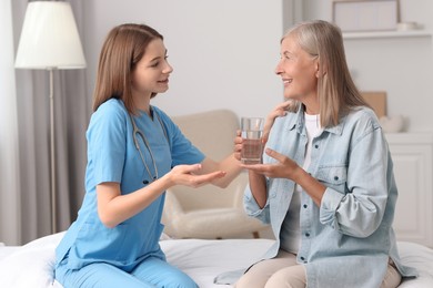 Photo of Young healthcare worker consulting senior patient on bed indoors