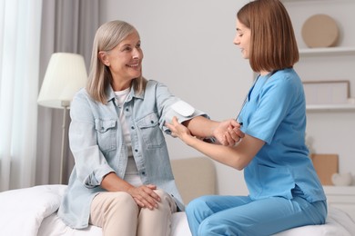 Photo of Healthcare worker measuring patient's blood pressure indoors