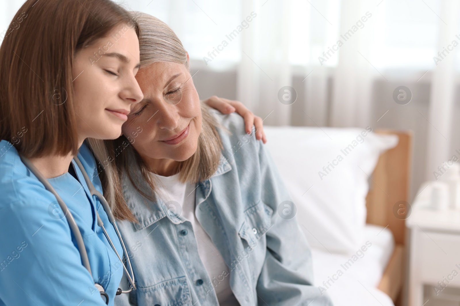 Photo of Young healthcare worker supporting senior patient indoors. Space for text