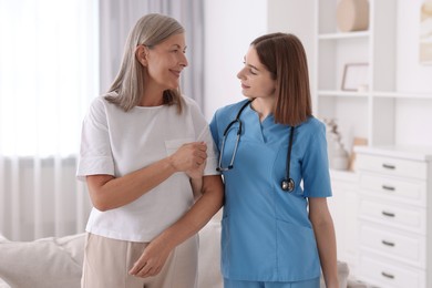 Young healthcare worker supporting senior patient indoors