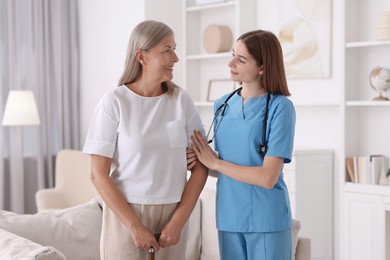 Young healthcare worker supporting senior patient indoors