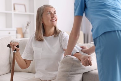 Photo of Healthcare worker measuring patient's blood pressure indoors, closeup