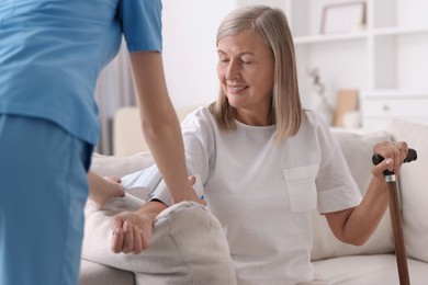 Photo of Healthcare worker measuring patient's blood pressure indoors, closeup