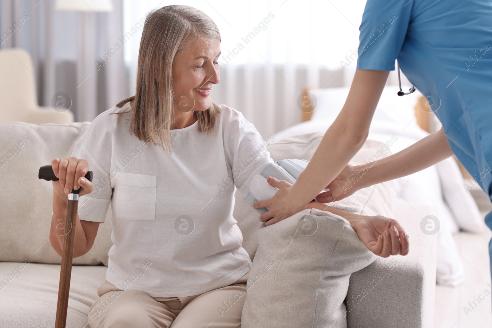 Photo of Healthcare worker measuring patient's blood pressure indoors, closeup