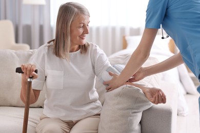 Healthcare worker measuring patient's blood pressure indoors, closeup