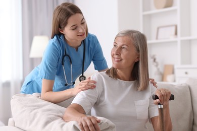 Smiling healthcare worker supporting senior patient indoors