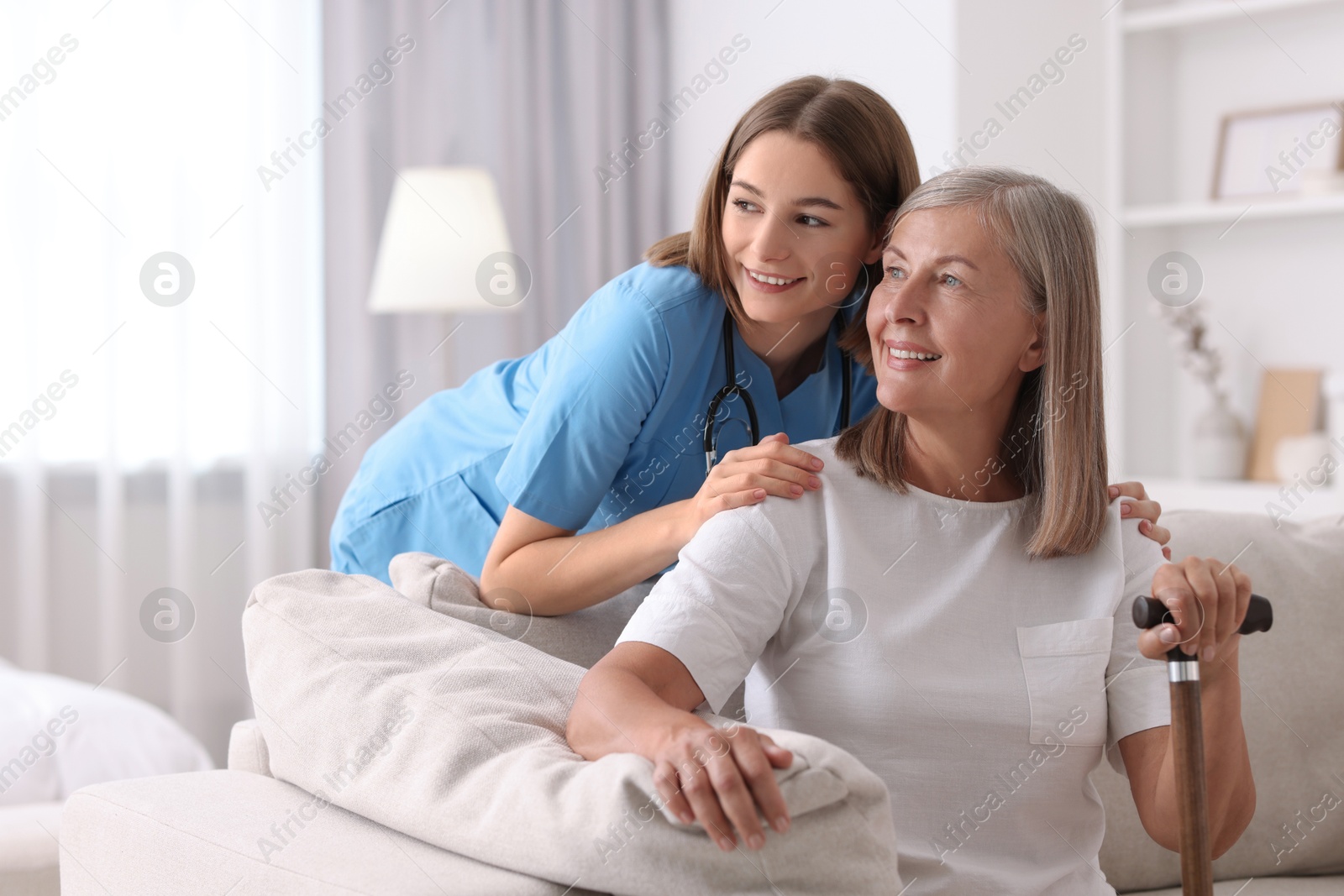 Photo of Smiling healthcare worker supporting senior patient indoors. Space for text