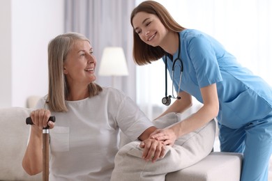 Photo of Smiling healthcare worker supporting senior patient indoors