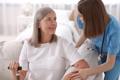 Young healthcare worker supporting senior patient indoors