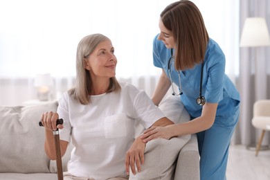 Photo of Young healthcare worker supporting senior patient indoors